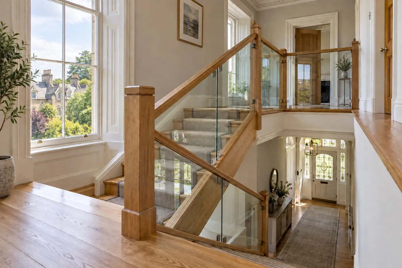 Oak handrail and newel posts with clear glass panels on a staircase and landing